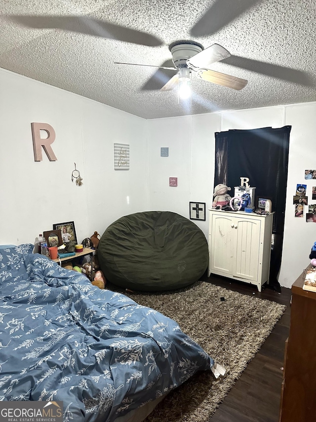 bedroom featuring dark wood-type flooring, a textured ceiling, and ceiling fan