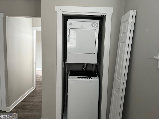 laundry area featuring stacked washer and dryer and dark wood-type flooring