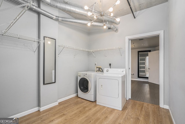 clothes washing area featuring hardwood / wood-style floors, an inviting chandelier, and washing machine and clothes dryer