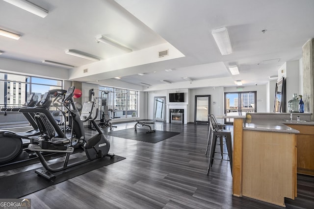 workout area featuring a view of city, visible vents, a wealth of natural light, and a glass covered fireplace