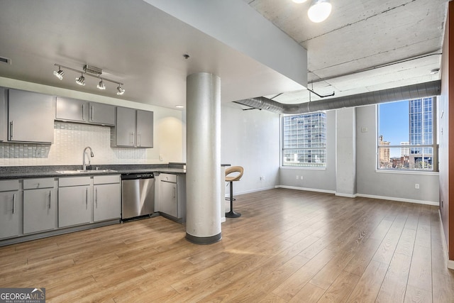 kitchen with decorative backsplash, gray cabinetry, light wood-type flooring, stainless steel dishwasher, and sink