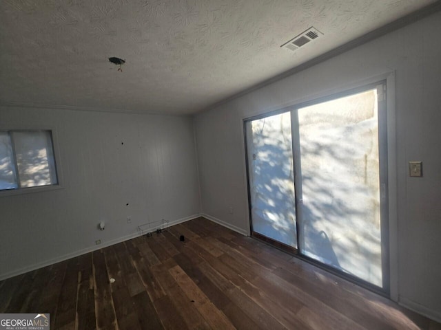 empty room featuring a textured ceiling and dark wood-type flooring