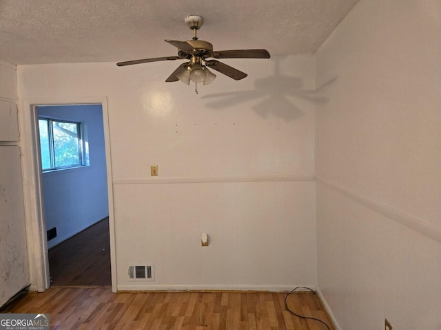 spare room with ceiling fan, light hardwood / wood-style floors, and a textured ceiling