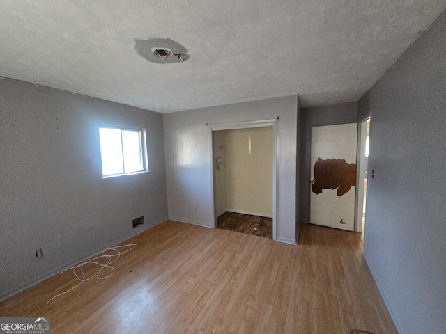 unfurnished bedroom featuring a textured ceiling, hardwood / wood-style flooring, and a closet