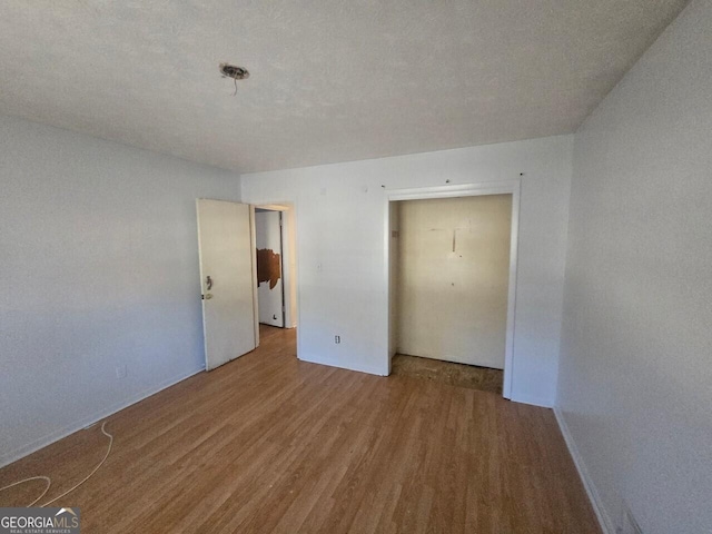 unfurnished bedroom featuring a textured ceiling, hardwood / wood-style flooring, and a closet