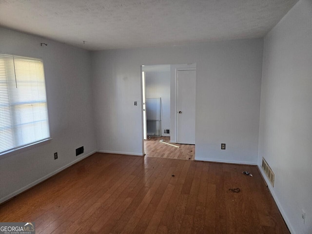 unfurnished room featuring a wealth of natural light, light hardwood / wood-style floors, and a textured ceiling