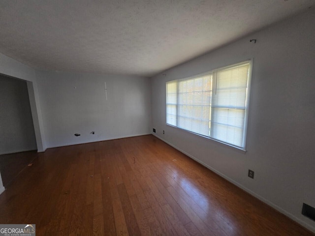 empty room with a textured ceiling and dark wood-type flooring