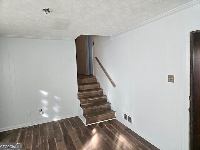 stairs featuring ornamental molding, a textured ceiling, hardwood / wood-style flooring, and wooden walls