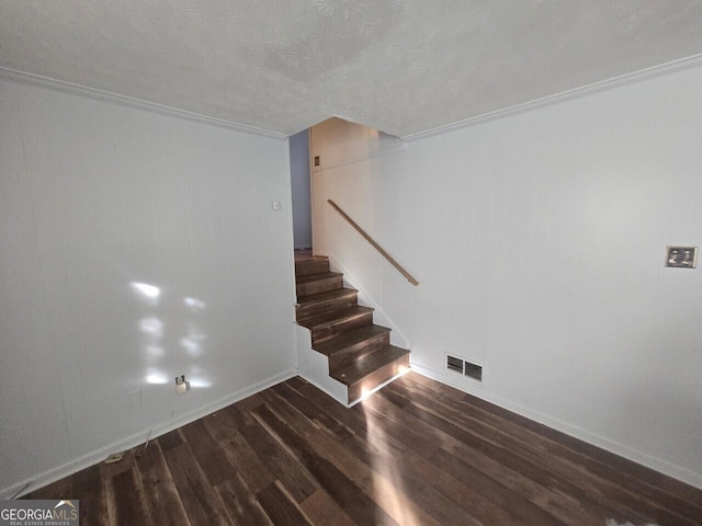 staircase with hardwood / wood-style floors, ornamental molding, and a textured ceiling