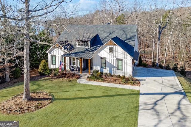 modern farmhouse featuring covered porch and a front lawn