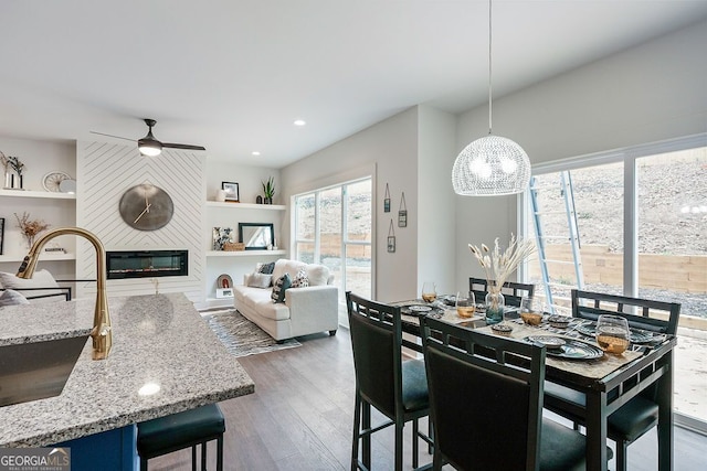 dining area with a large fireplace, wood finished floors, a ceiling fan, and recessed lighting