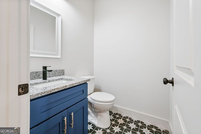 bathroom featuring baseboards, vanity, toilet, and tile patterned floors