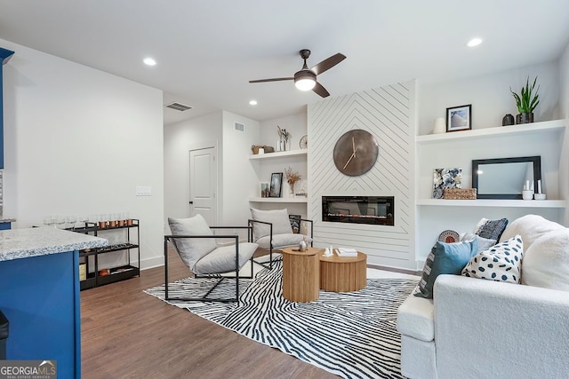 living area with built in features, visible vents, wood finished floors, a fireplace, and recessed lighting