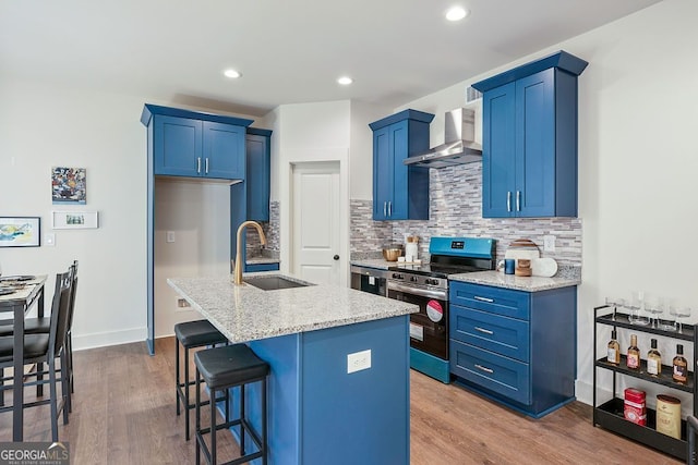 kitchen with wall chimney exhaust hood, electric range, blue cabinetry, and a sink