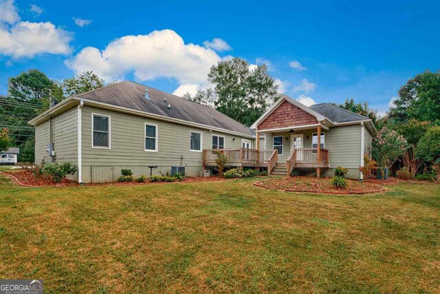 rear view of property featuring a lawn, ceiling fan, and a deck