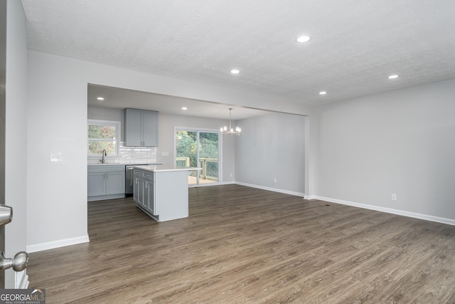 kitchen with sink, hanging light fixtures, decorative backsplash, gray cabinets, and a kitchen island