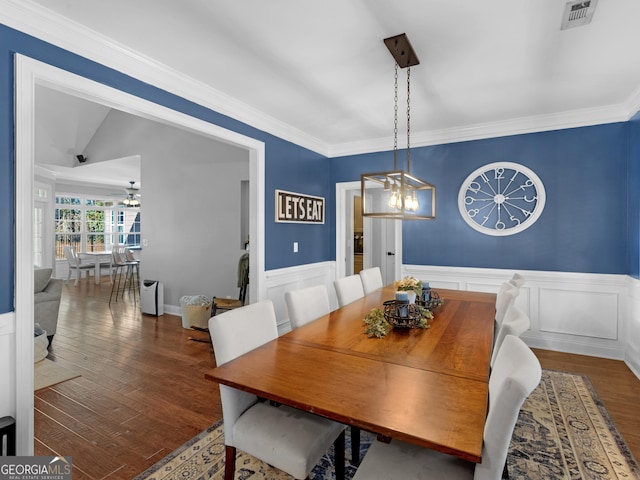 dining area with dark hardwood / wood-style flooring, vaulted ceiling, an inviting chandelier, and crown molding