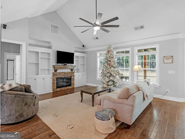 living room featuring high vaulted ceiling, a stone fireplace, built in shelves, ceiling fan, and dark hardwood / wood-style flooring