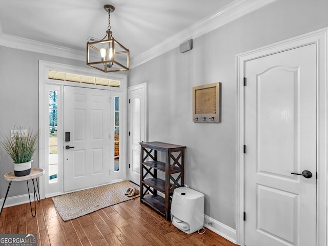 foyer with ornamental molding, dark hardwood / wood-style floors, and an inviting chandelier