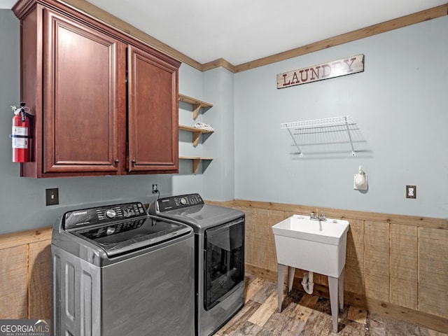 washroom featuring cabinets, washing machine and dryer, and light hardwood / wood-style flooring