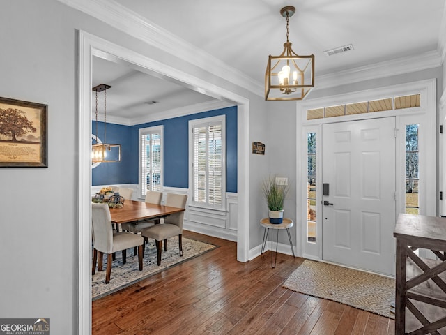 foyer entrance featuring ornamental molding, dark hardwood / wood-style floors, and an inviting chandelier