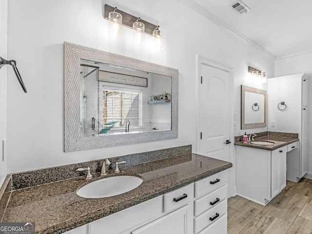 bathroom with vanity, wood-type flooring, crown molding, and walk in shower