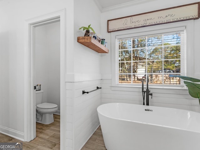 bathroom with hardwood / wood-style flooring, a washtub, toilet, and ornamental molding