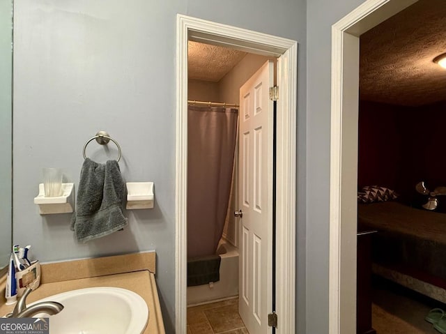 bathroom featuring tile patterned flooring, sink, shower / tub combo, and a textured ceiling