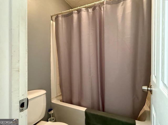 bathroom with shower / bath combination with curtain, a textured ceiling, and toilet