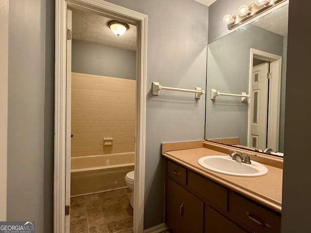 full bathroom with vanity, tiled shower / bath combo, a textured ceiling, and toilet