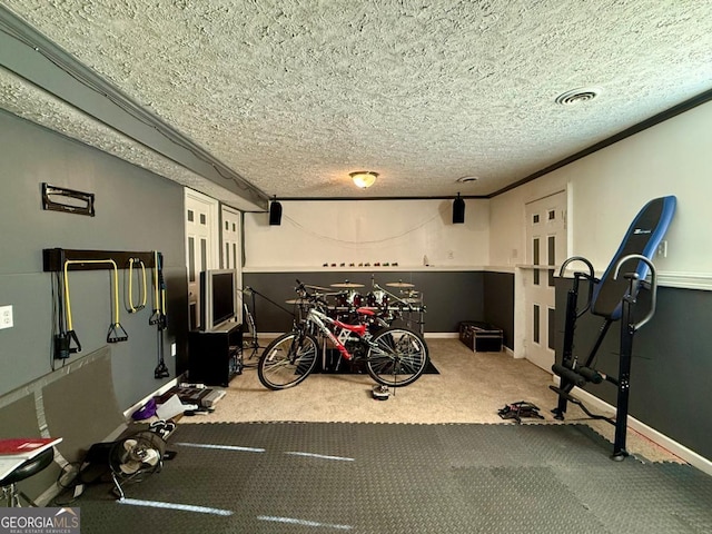 exercise area with carpet flooring, ornamental molding, and a textured ceiling