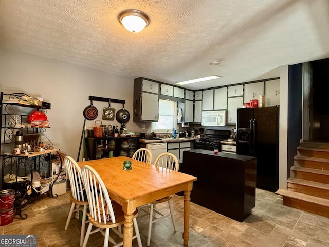 kitchen featuring sink, a textured ceiling, a center island, and black appliances