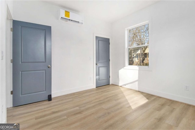 empty room with light hardwood / wood-style floors and an AC wall unit