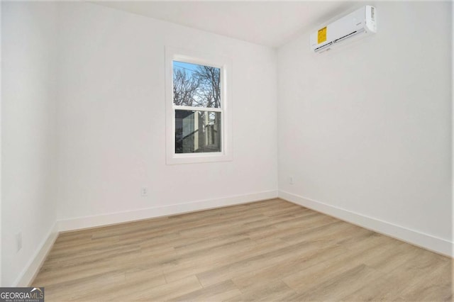 spare room featuring a wall unit AC and light hardwood / wood-style floors