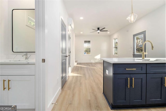 kitchen with ceiling fan, sink, pendant lighting, and light hardwood / wood-style flooring