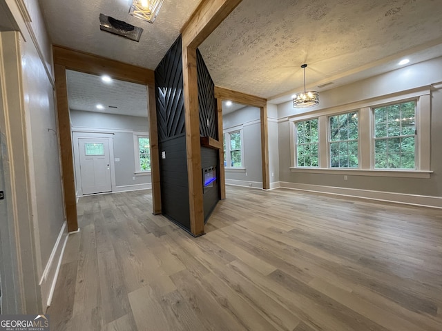 interior space with a fireplace, a textured ceiling, hardwood / wood-style flooring, and an inviting chandelier