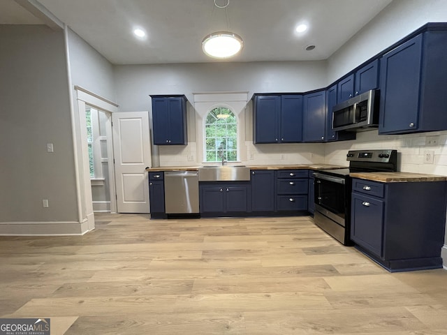 kitchen with sink, blue cabinets, light wood-type flooring, and appliances with stainless steel finishes