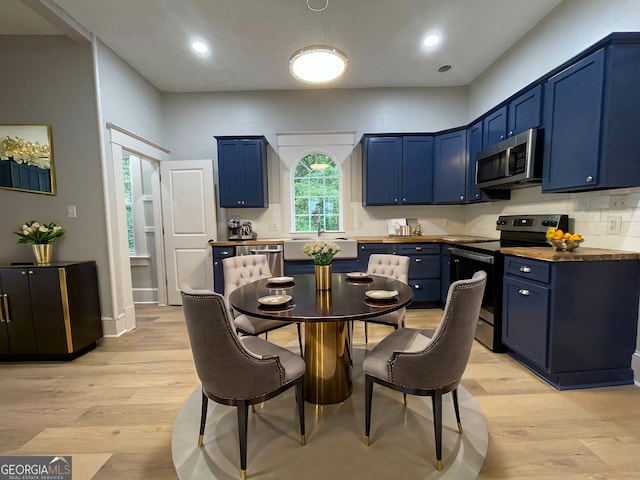 kitchen with blue cabinetry, light wood-type flooring, stainless steel appliances, and sink