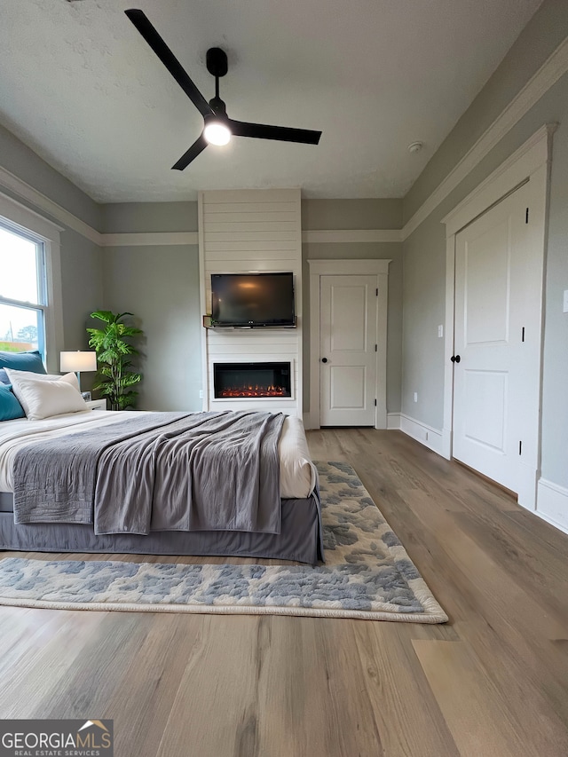 bedroom featuring a fireplace, hardwood / wood-style floors, and ceiling fan