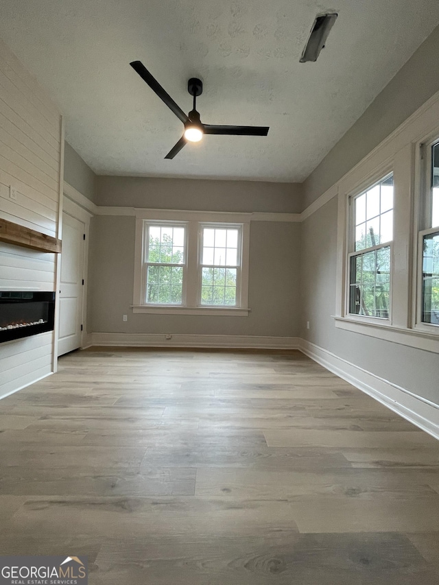 interior space featuring ceiling fan, a large fireplace, and light wood-type flooring