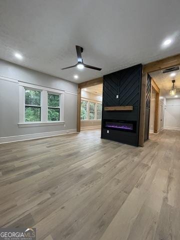 unfurnished living room featuring ceiling fan, a large fireplace, and hardwood / wood-style flooring