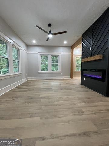 interior space featuring ceiling fan, a large fireplace, a wealth of natural light, and light hardwood / wood-style flooring