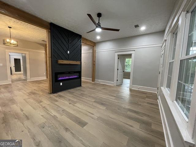 unfurnished living room featuring a fireplace, hardwood / wood-style floors, and ceiling fan with notable chandelier