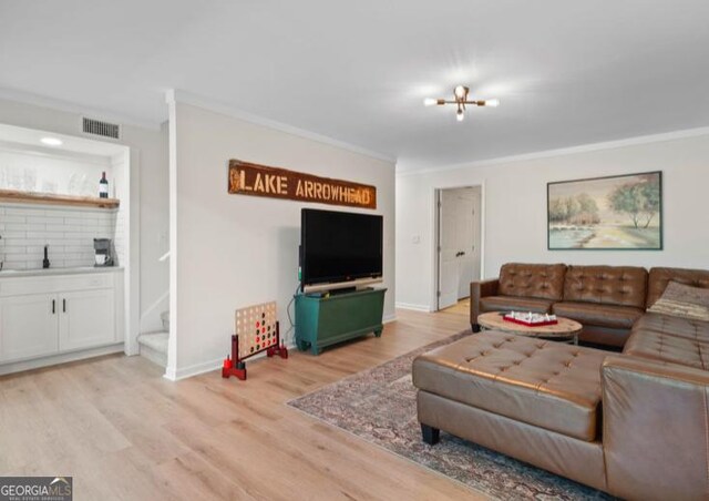 living room featuring sink, light hardwood / wood-style floors, and ornamental molding