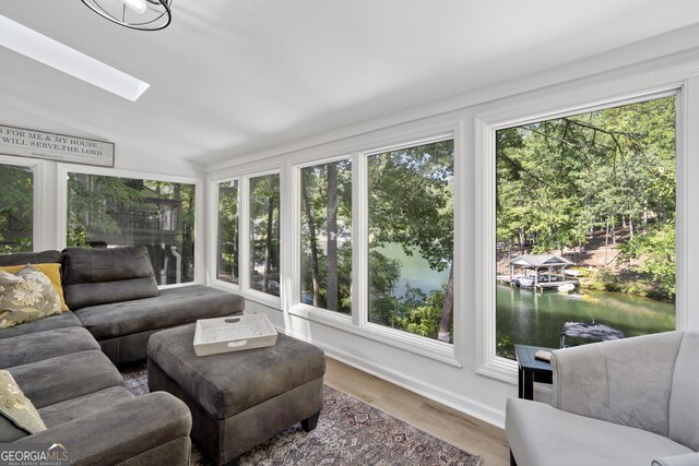 sunroom / solarium with plenty of natural light, a water view, and vaulted ceiling with skylight