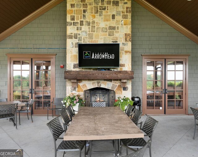 exterior space with an outdoor stone fireplace, high vaulted ceiling, and french doors