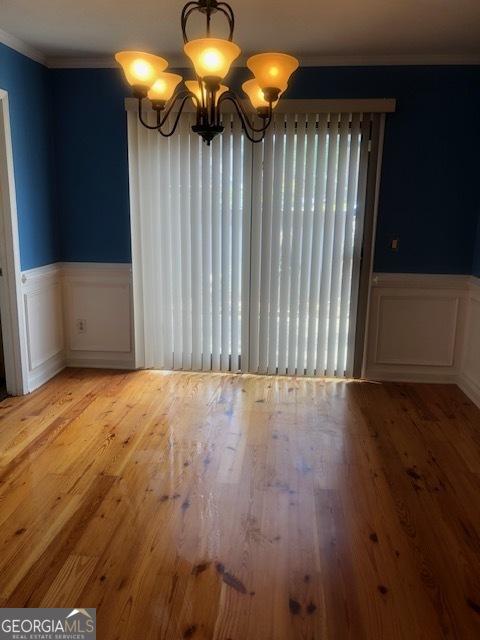 unfurnished dining area with light hardwood / wood-style floors, ornamental molding, and a notable chandelier