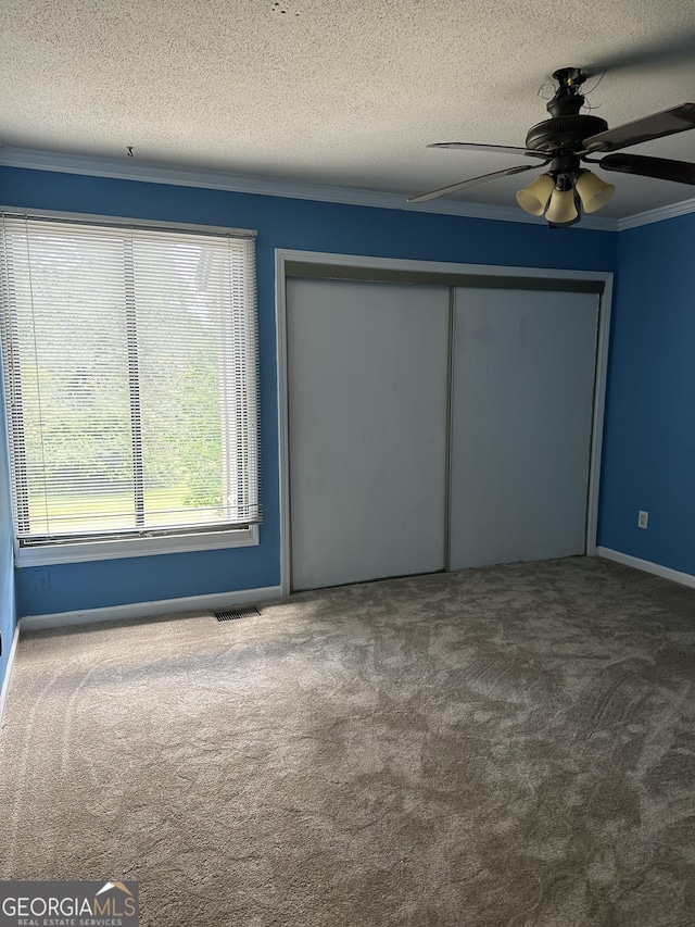 unfurnished bedroom featuring ceiling fan, a closet, a textured ceiling, and dark colored carpet