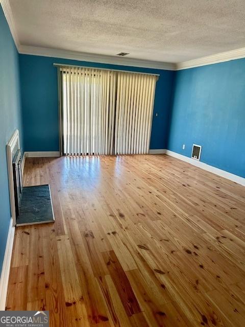 unfurnished room featuring crown molding, a textured ceiling, and light hardwood / wood-style flooring