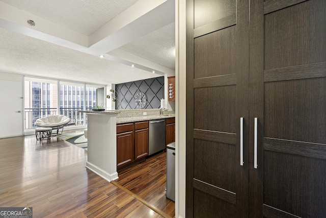 kitchen featuring dishwasher, a textured ceiling, dark hardwood / wood-style floors, and light stone countertops